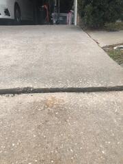 The slabs of the homeowner's concrete driveway had settled significantly due to the erosion of the underlying soil, creating major tripping hazards.