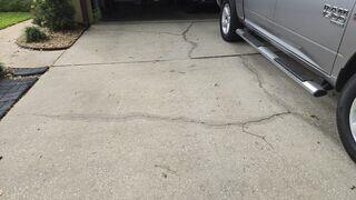 Soil settlement beneath the driveway had caused the concrete to sink and develop numerous cracks.