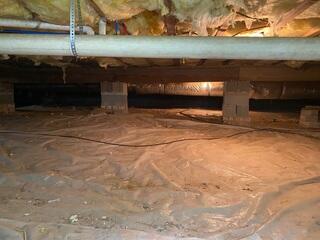 Before work began, the crawl space had exposed ground covered only by a thin vapor barrier, leaving the home vulnerable to moisture intrusion and elevated humidity.