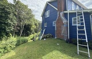 Comprehensive prep work shields masonry and windows while painting elevated siding.