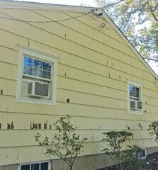 A close-up view of the weathered siding showing the extensive scraping required to remove failing layers.