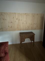 Enclosed wall cutout featuring vertical wood paneling above a wooden desk.