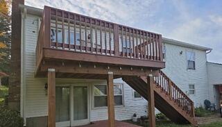 Fully refinished two-story deck with a rich, protective wood stain on upper levels, lower patio decking, and exterior stairs