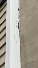 Before repair: Deteriorated joint caulking and peeling trim paint along the stucco line needing restoration.