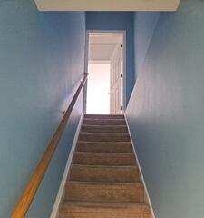 After: Brightly transformed stairwell painted in crisp sky blue to match the remodeled basement.