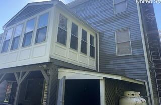 Meticulous scraping and spot priming worn cedar siding to ensure maximum paint adhesion and protection.
