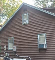 Thorough surface inspection and spot-priming prep on a log home exterior in Danbury, CT.