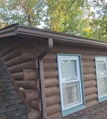Crisp, clean light-blue window trim application on dormers contrasting against dark log siding
