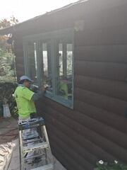 Precision detail work painting light-blue accent trim around lower-level window frames.