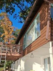 High-angle exterior view highlighting clean wood siding trim, window frames, and structural deck support restoration.