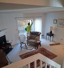 Professional interior painter meticulously prepping and coating trim and high-reach wall areas in a spacious Shelton, CT living room