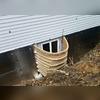 The soil surrounding the home has been removed to install the RockWell Egress Window Well and the wall anchors. SilverGlo has been installed externally on the foundation to prevent moisture from seeping in and to help insulate the basement.