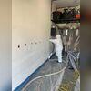 Holes are cut between each set of studs in the wall frame and Rock Wool insulation is blown in.