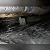 During the crawl space inspection, water and moisture damage are visible. Water is pooling on the vapor barrier, and water lines are seen on the foundation walls where the water is seeping out.