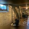 Early stages of encapsulation reveal exposed block walls and a dehumidifier in place. While some plastic sheeting is installed, the basement still faces humidity and energy efficiency challenges.