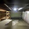 This photo shows the basement in its original condition, with visible water on the concrete floor indicating active intrusion. The space was vulnerable to moisture-related damage, prompting the need for a full waterproofing and humidity control solution.
