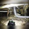 This crawl space in poor condition, with visible moisture, dirt, and heavy debris scattered across the floor. The environment is unsealed and vulnerable to humidity, mold growth, and structural deterioration, creating an unhealthy space beneath the home.
