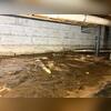 During the inspection, mud and water are visible all over the old vapor barrier. Water lines are visible in the concrete block wall, meaning water is seeping through.