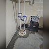 The sump pump collects water from the sub-floor drainage system and pumps it up and out of the basement through the white discharge lines.