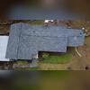 This aerial view shows a completed roofing system with clean, even shingle lines across the main roof sections.