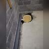 Positioning the sump pump in its pit, preparing it to protect the home from potential flooding.