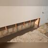 We ran our subfloor drains around the corner of the foundation so we could install the sump pump in the utility room. Our subfloor drains are relatively easy to install, and as you can see, we only needed to remove the drywall about 18 inches high and the studs about a foot high from the floor in...