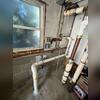This photo shows the completed interior portion of the one-point radon mitigation system. New piping has been installed from the extraction point and routed toward the rear exterior of the home. The system is designed to draw radon from beneath the foundation and vent it safely outside.
