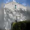 Completed exterior view showing the new radon piping routed along the left side of the home.