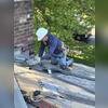 A crew member carefully installed flashing where the chimney meets the roof. These metal components help direct water away from the chimney connection, protecting an area that requires particular attention during roof replacement.