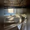 A white vapor barrier covers the ground and extends along the foundation walls beneath this La Habra home. The material is fitted around a vertical plumbing pipe and beneath the crawl space access opening.