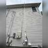 Completed exterior radon piping and fan routed alongside the chimney, with the vent extending above the roofline.